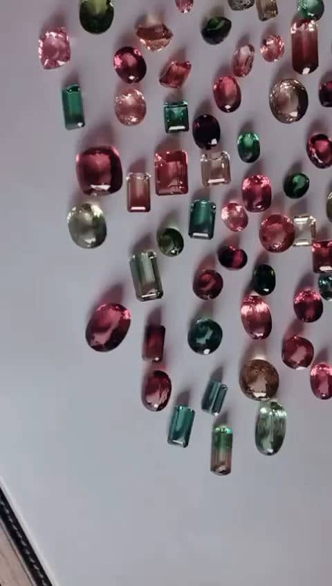 A laid-out selection of faceted tourmaline in pink, red, green and bi-colour, viewed across the parcel.